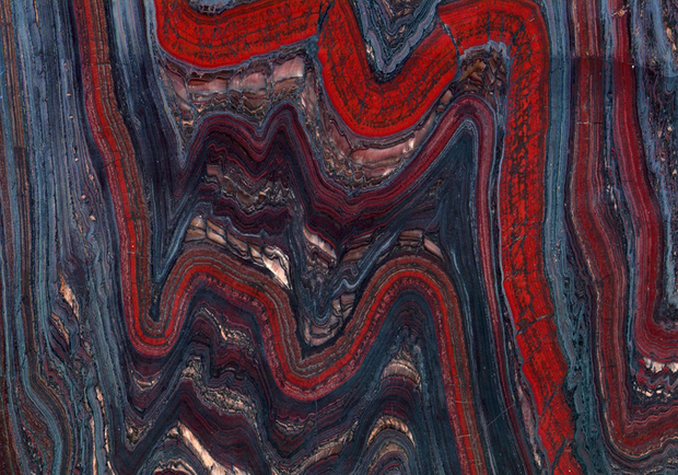 Close-up image of folded red-and-black banded iron-formation with golden tiger-eye pockets.